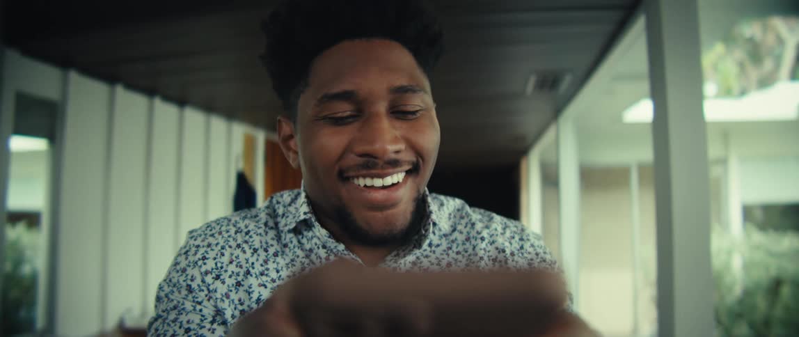 The man texts on his phone and smiles