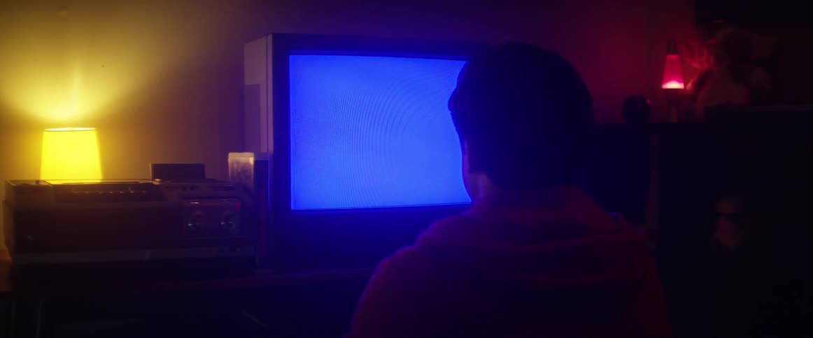 A man sits in front of an old tube television