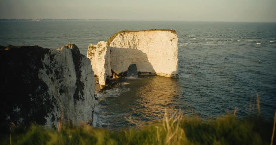 White cliffs rising above the sea with a natural arch at the base