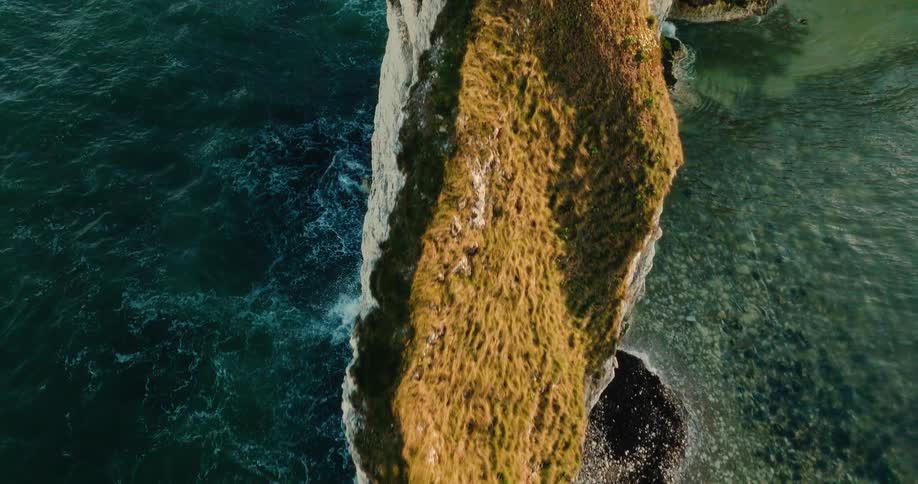 Narrow cliff ridge with vegetation extending into the sea