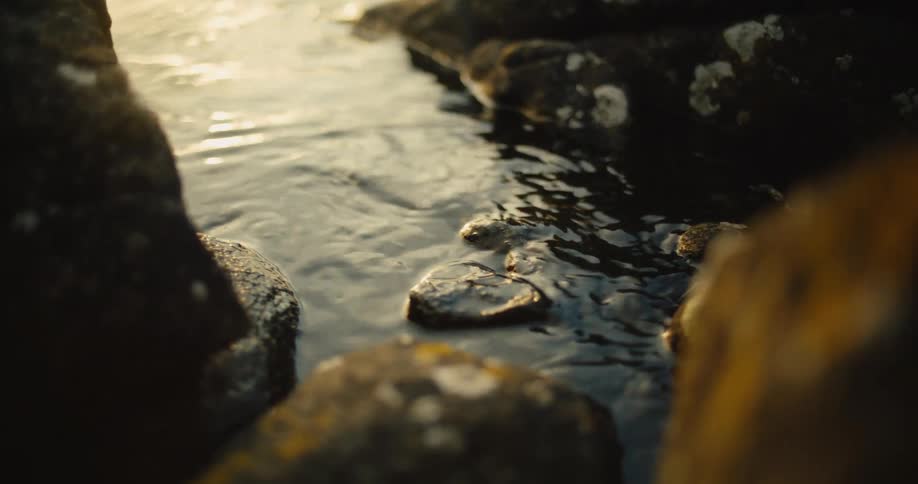 Flowing water between rocks at sunset