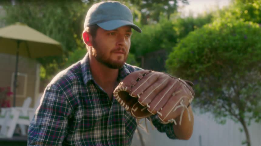 Man adjusts hat and throws a baseball