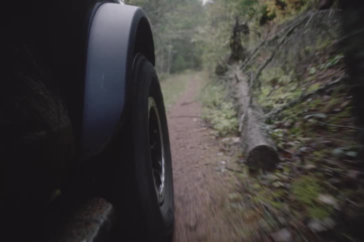 Automobile tire moves as it travels on a dirt road through the forest