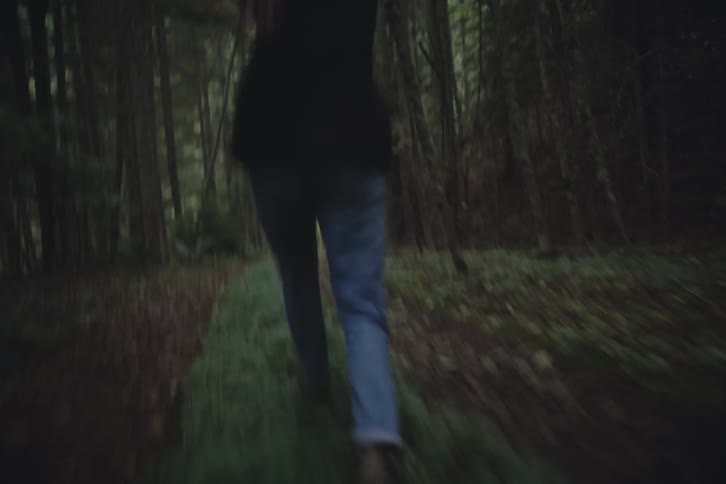 Person frolicking on a path through the woods outdoors during day time