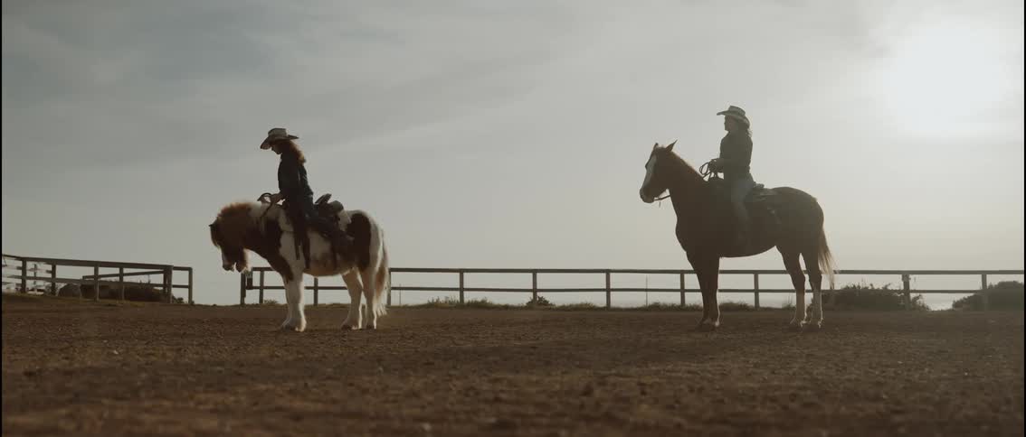 A women and her daughter riding horses outdoors