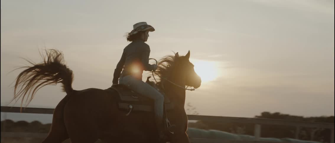 A woman riding a horse around in a pen