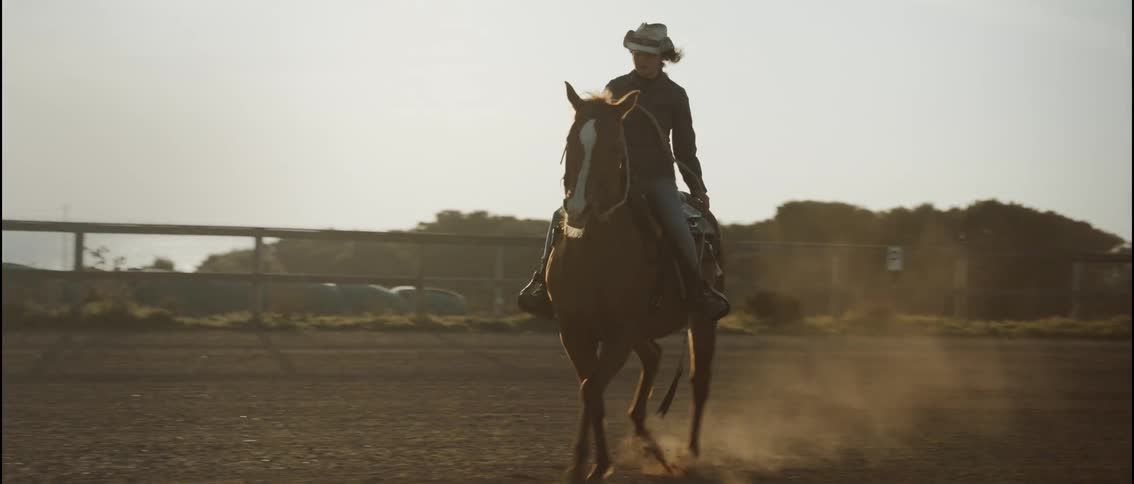 The woman rides her horse in the corral