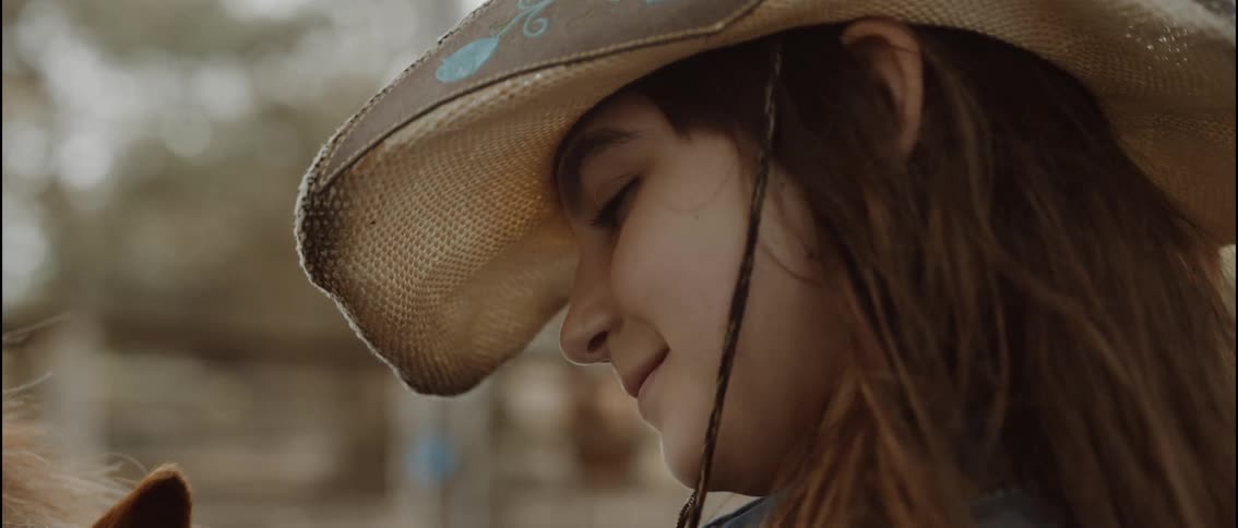 The girl is smiling at the horse