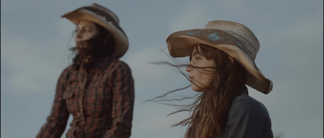 A women and her daughter wearing cowboy hats outdoors