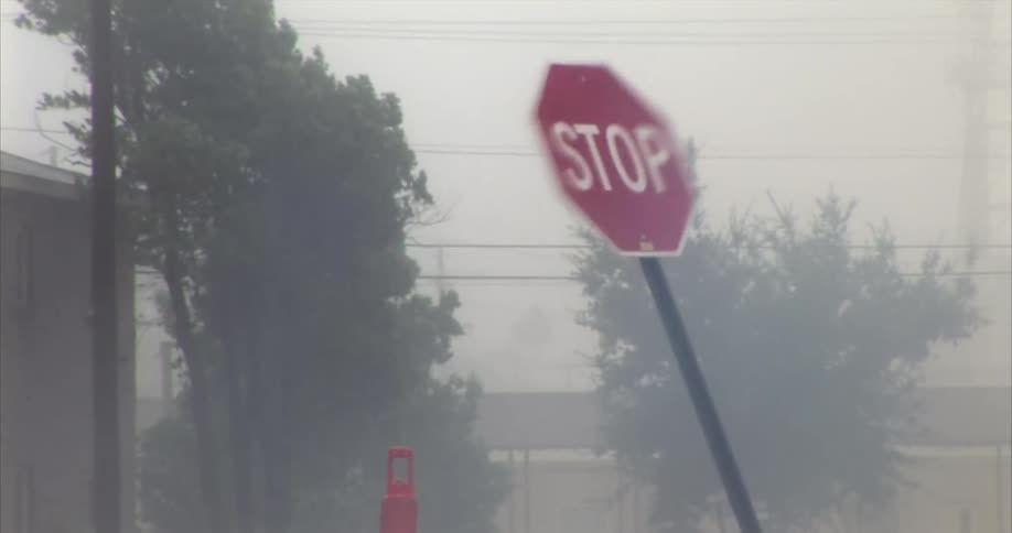 Stop sign tilted by wind on a lowvisibility street with trees in the background