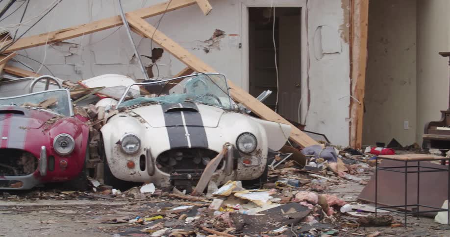 Piano next to cars destroyed by a collapsed house on the coast among debris and destruction left by the storm