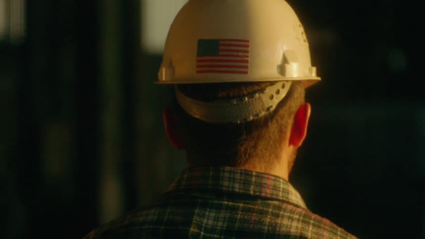 A man wears a hard hat with an american flag sticker