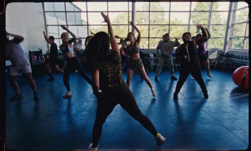 A female instructor leads a group of men of women in an indoor aerobics class