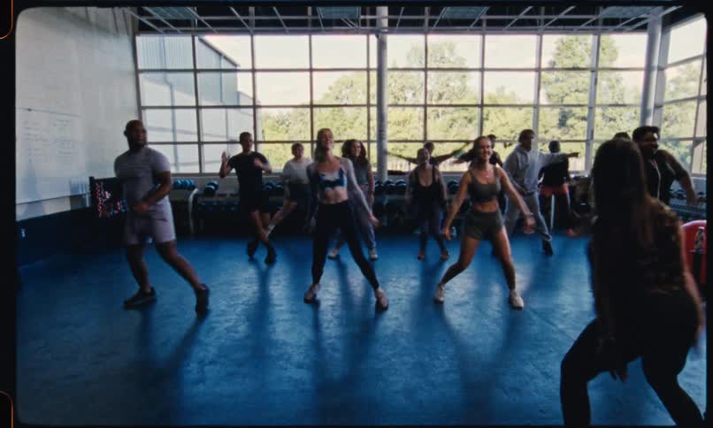 An instructor leads a group fitness class through aerobic exercises
