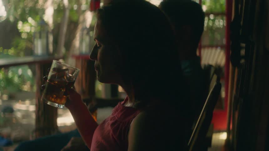 Woman sitting on a balcony takes a sip of a drink