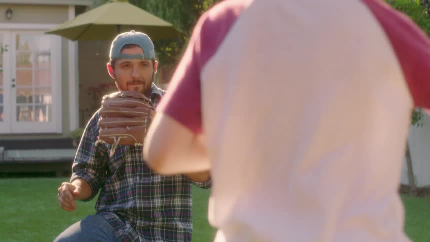 A dad plays catch with his son
