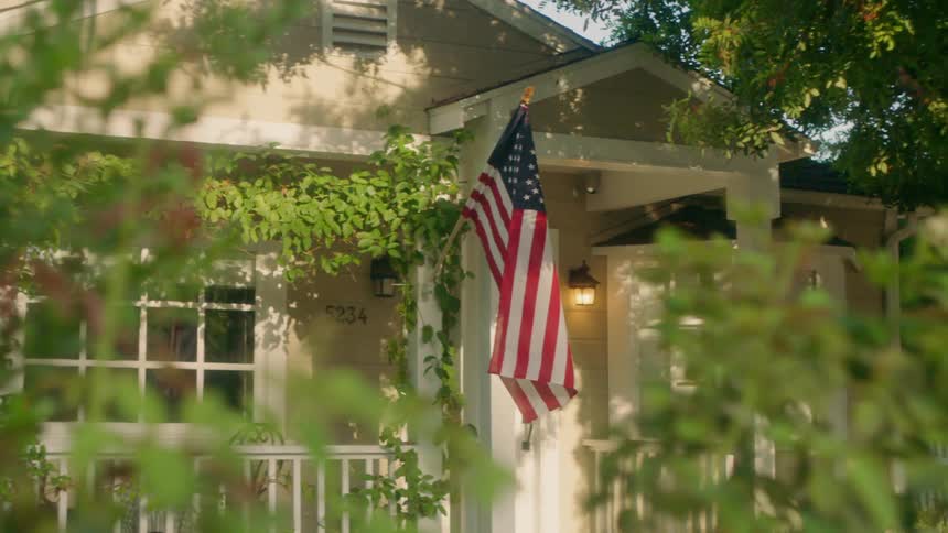American flag hanging from a home on sunny day