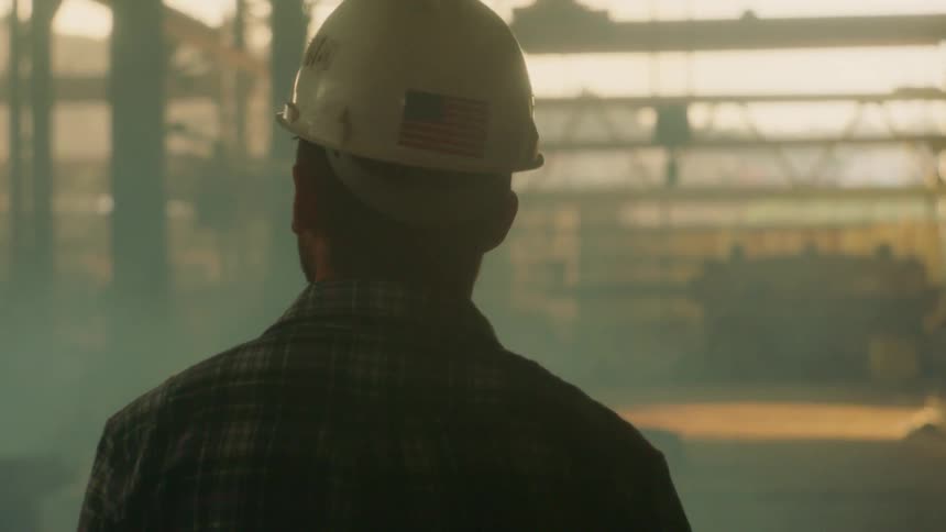 Bearded man wearing a hard hat walking around looking at his work site outdoors