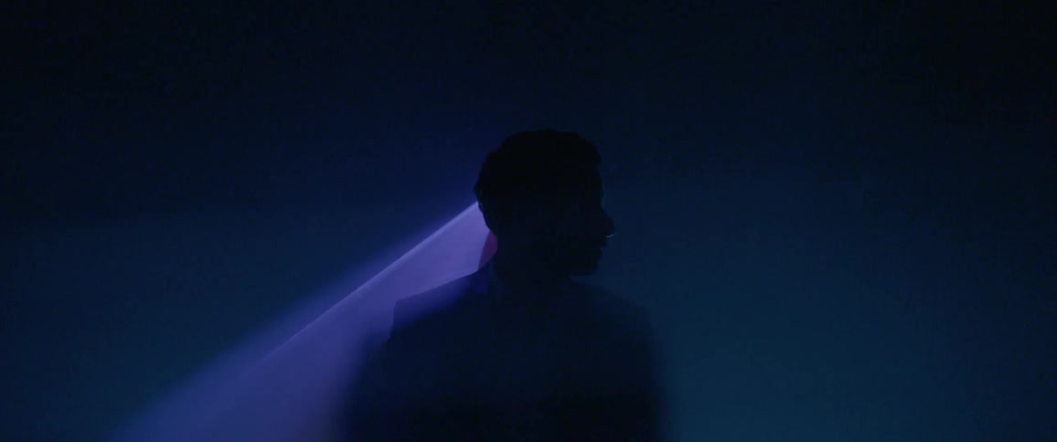 Man standing in a dark room with lasers behind his head