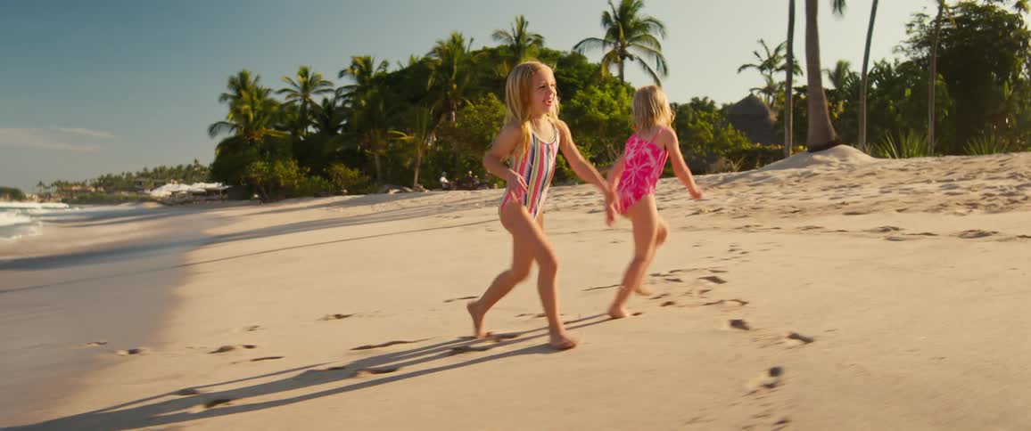 Two children running on the beach together