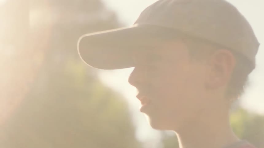 A boy wearing a cap and glove tosses a baseball