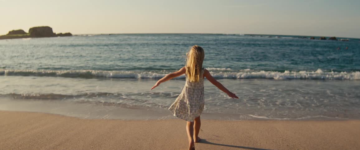 Girl walking toward the sea leaving footprints in the sand