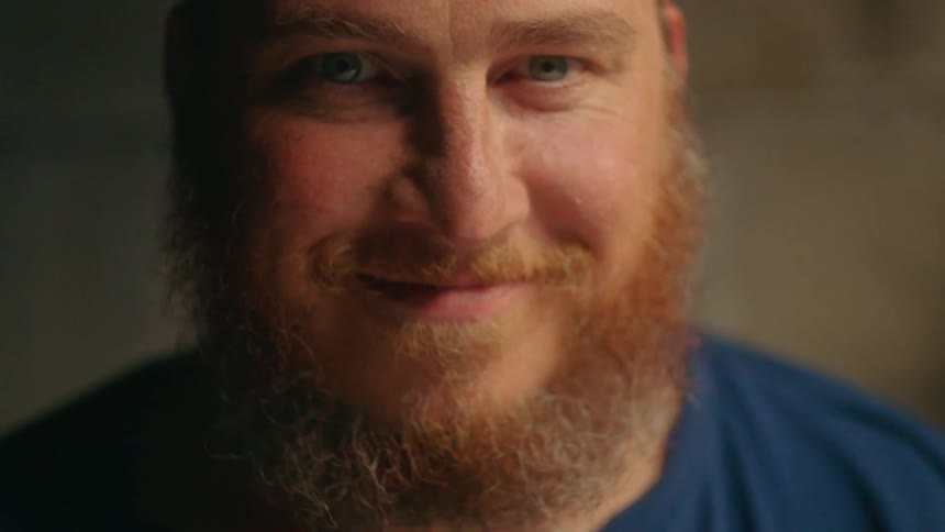 Man with a beard looks down