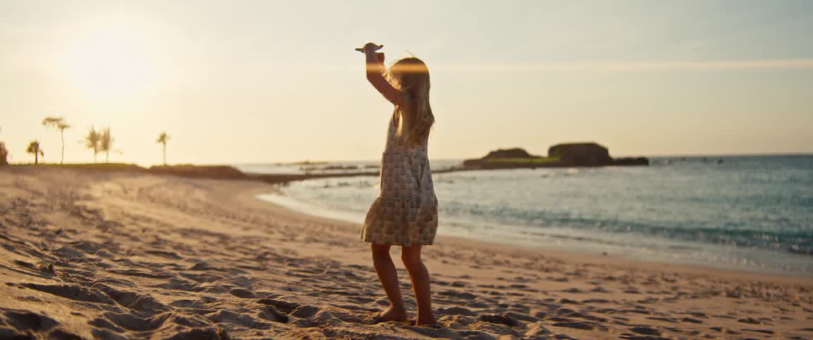 Girl in a dress twirls and curtsies on the beach