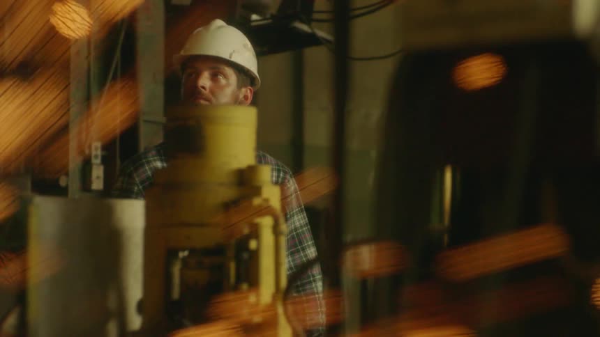 Sparks fly in front of a worker wearing a hardhat