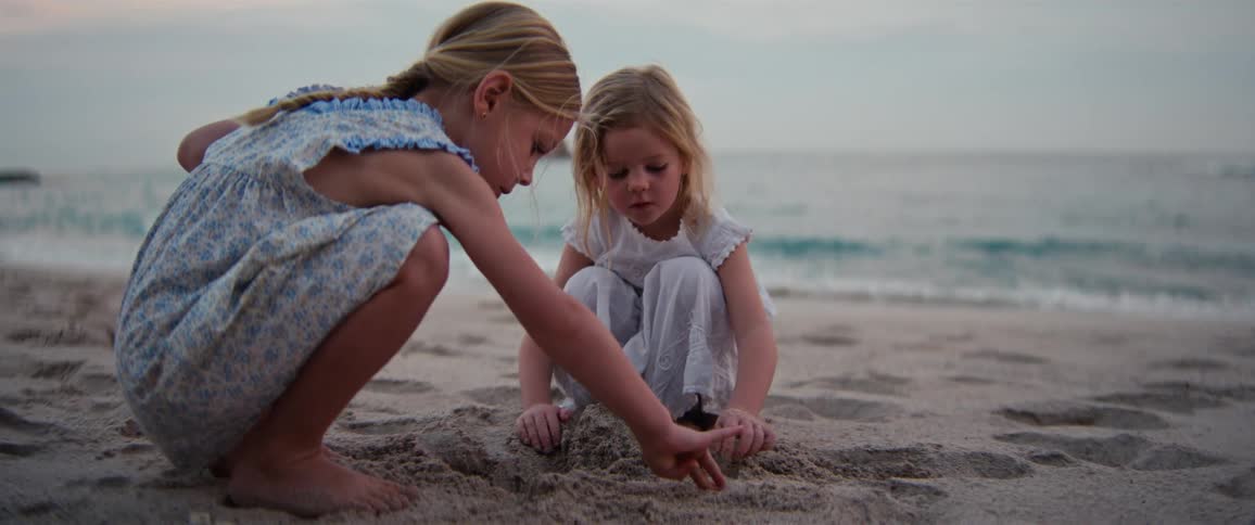 Two young girls are playing in the sand on a beach
