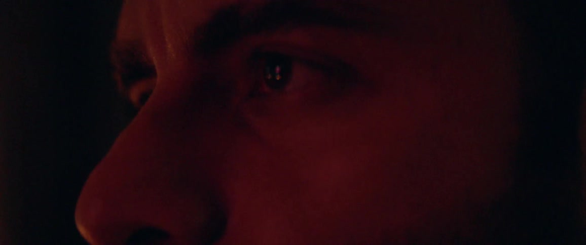 A man watches something in a dim room