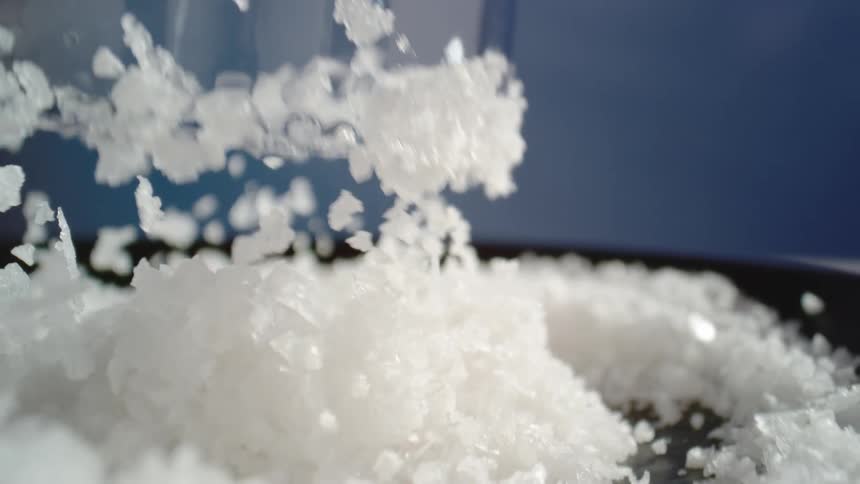 Glass lifts and the white flakes either cling to it or fall to join others in a black dish