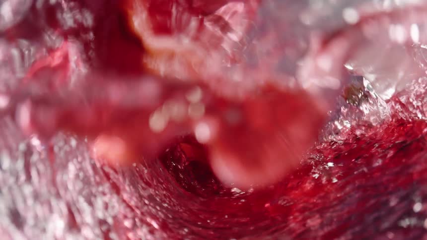 Red liquid with ice and a slice of lemon swirling