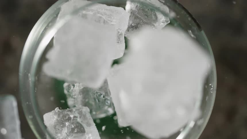 Ice cubes fall into a glass