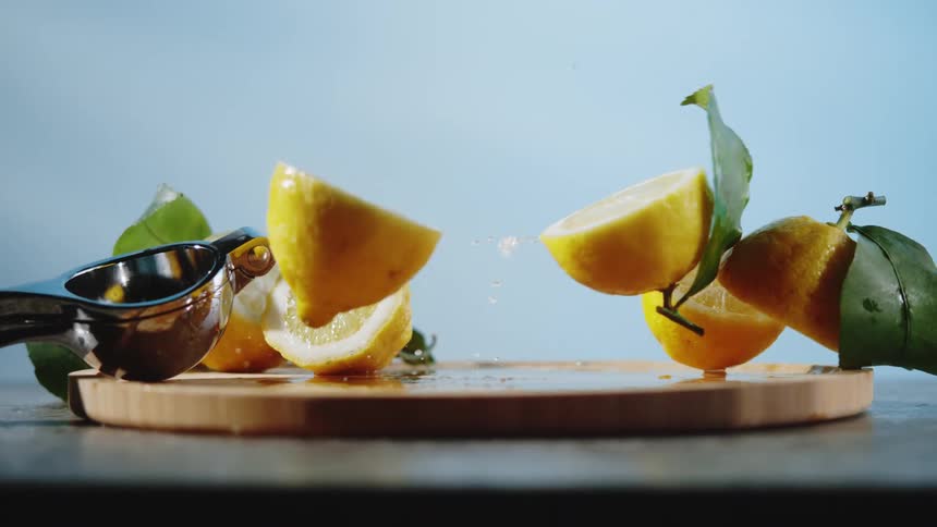 Halved lemon falls into pieces after landing on a wooden chopping board