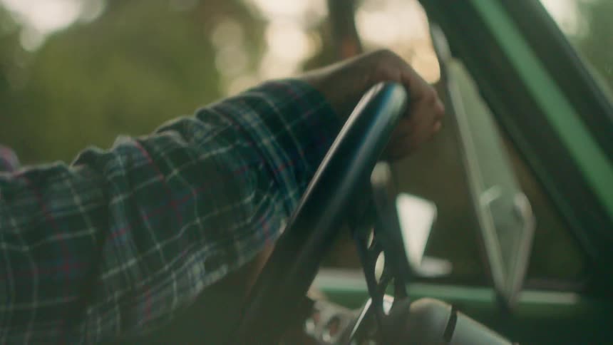 Close-up of a man driving a vehicle at sunset