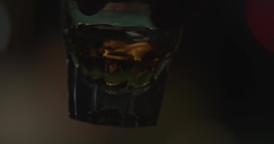 Close up of hand holding a small glass with liquid in it