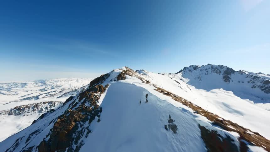 Snow covers a portion of a mountain ridge in mountainous terrain on a winter day