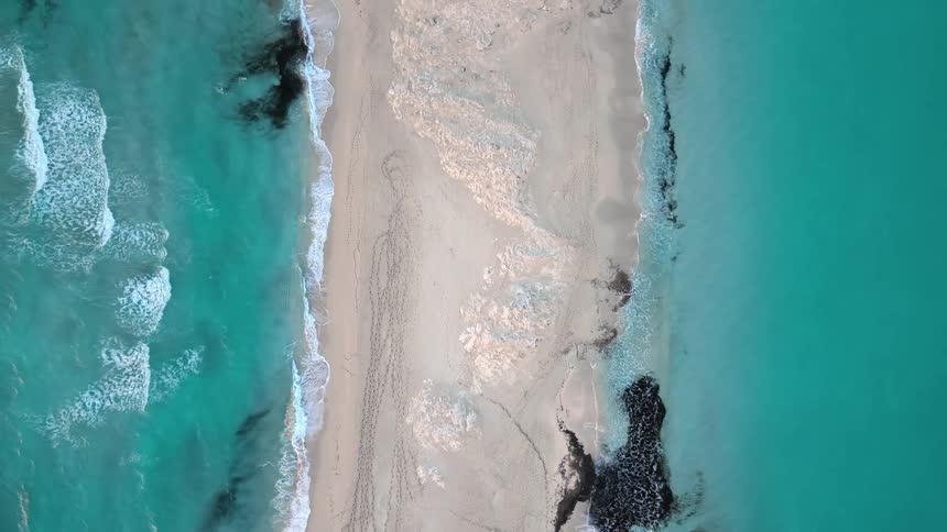 Clear water waves roll over white sand on the coast