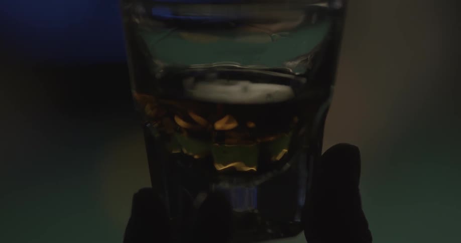 A man holds up a glass of liquor