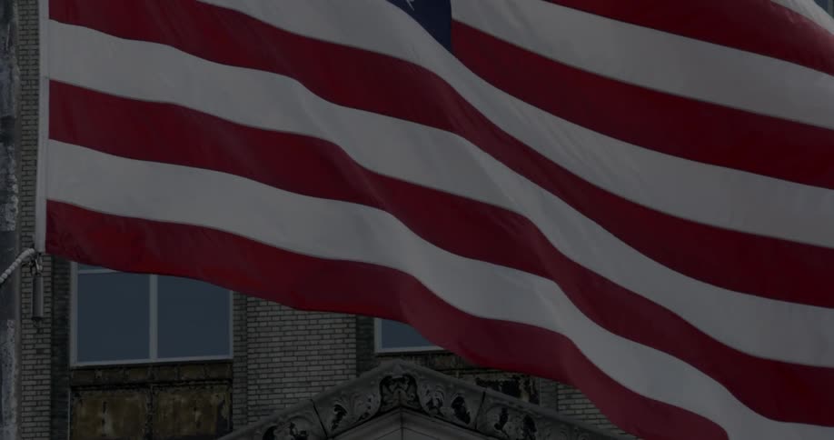 An american flag billows in front of a building