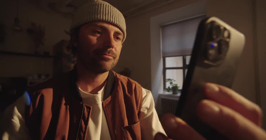 Man sitting at home lifts his smartphone to view it