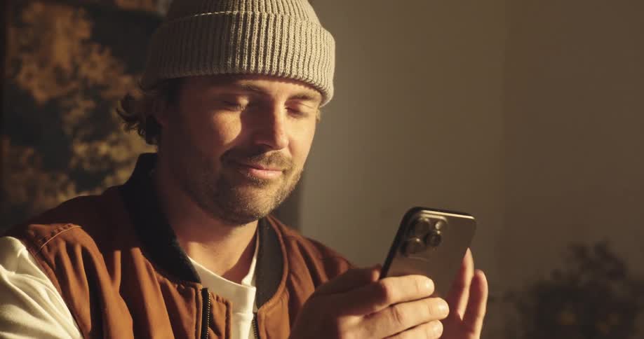 close up tele shot of a working man using his smartphone in a sunny indoor setting
