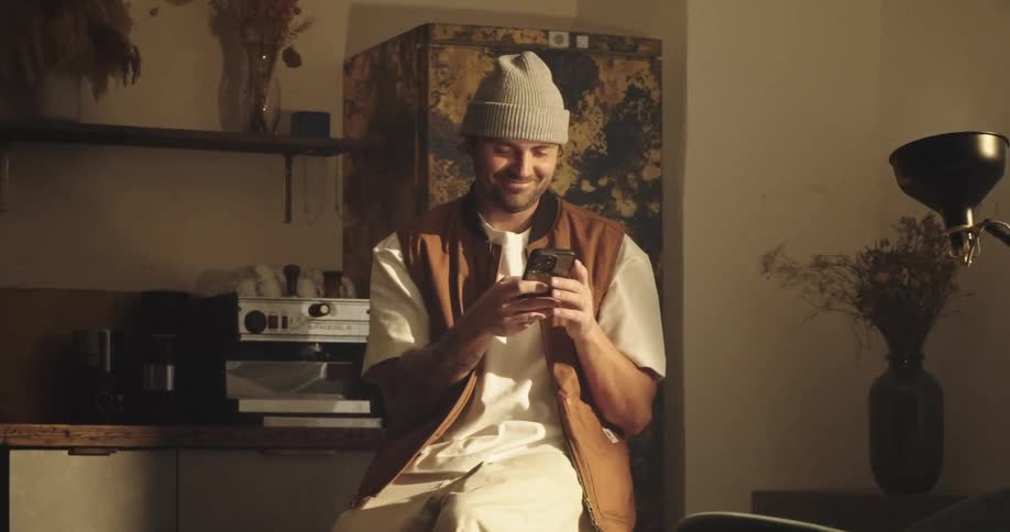 Man sitting indoors smiling while using smartphone
