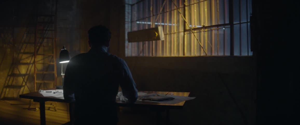 A man sketches on a table in a dark room