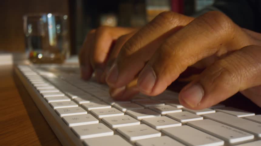 Mans fingers typing on a computer keyboard