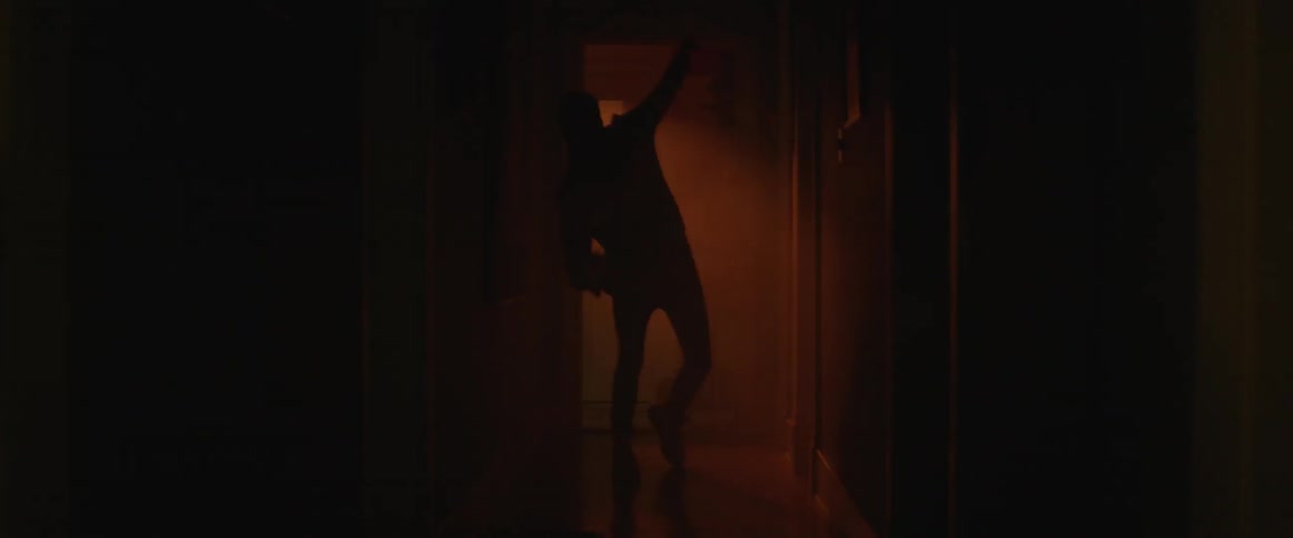 A man dances in a dark hall with flashing lights