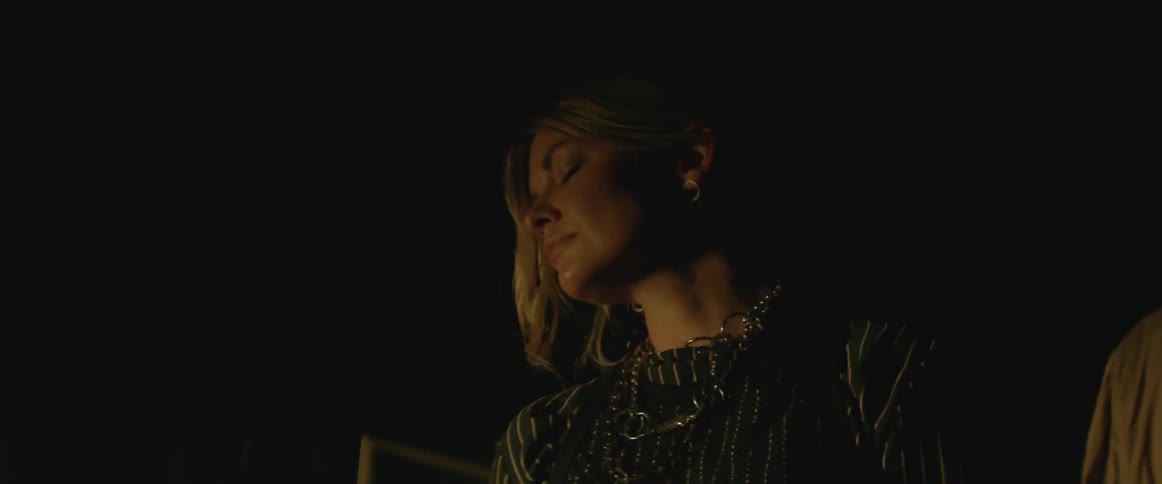 Woman standing in a dark room with light flashing on her