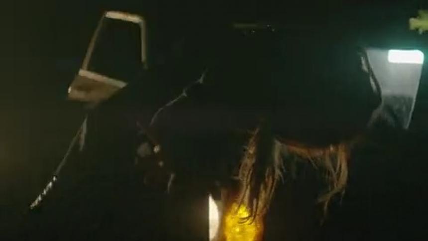 A woman dances outside a car in a flashing light