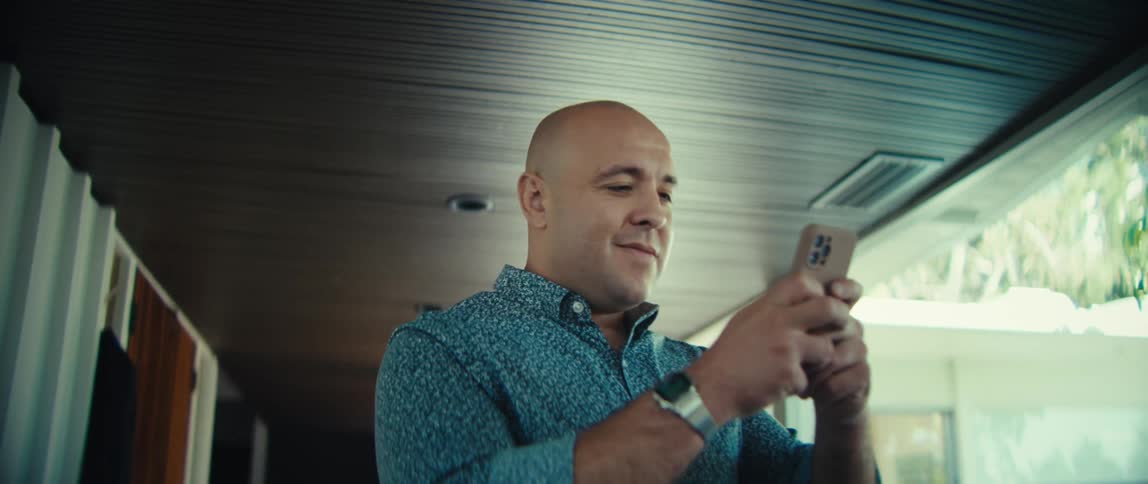 Man standing uses a smartphone with both hands in an indoor hallway